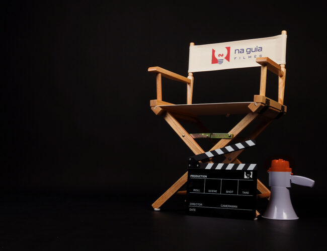 White director chair with clapper board and megaphone on black background.