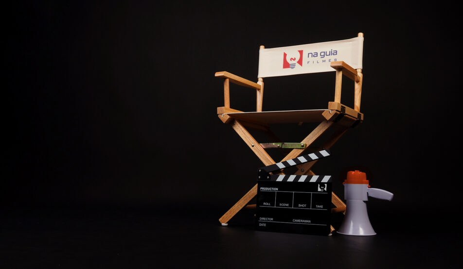 White director chair with clapper board and megaphone on black background.